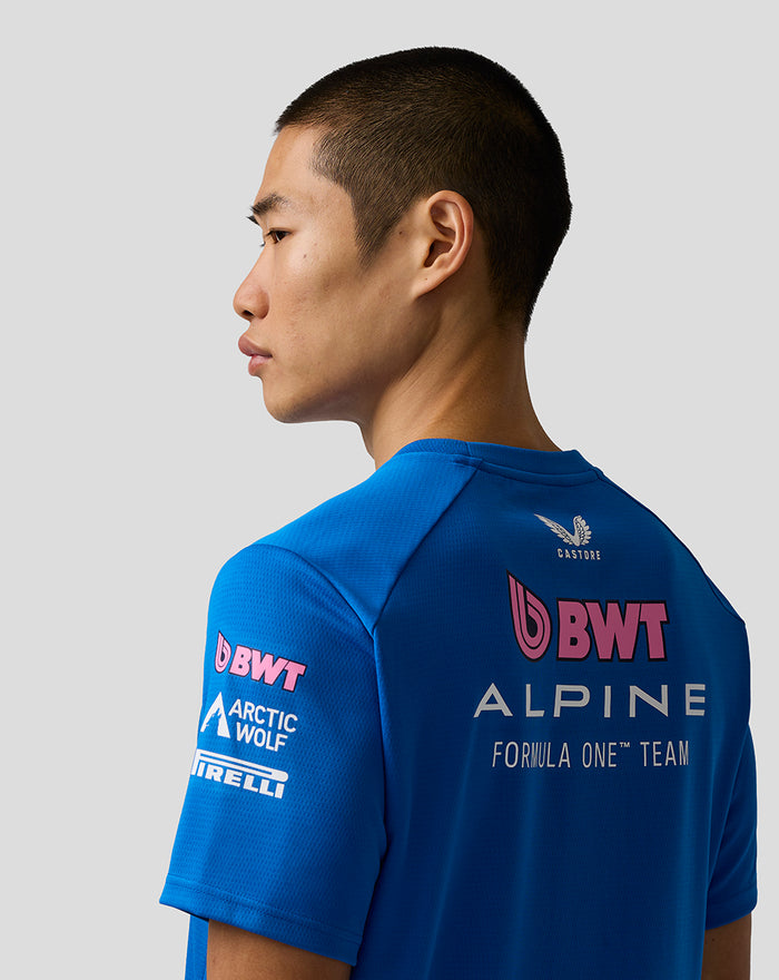Side view of male model in blue BWT Alpine Formula One Team Set Up T Shirt, showing back logo and shoulder contrast piping