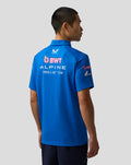 Back view of a blue BWT Alpine Formula One Team polo shirt worn by a model, with team logos on the back.