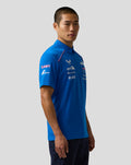 Side view of a man in a blue BWT Alpine Formula One Team polo with sponsor logos on the chest and sleeve