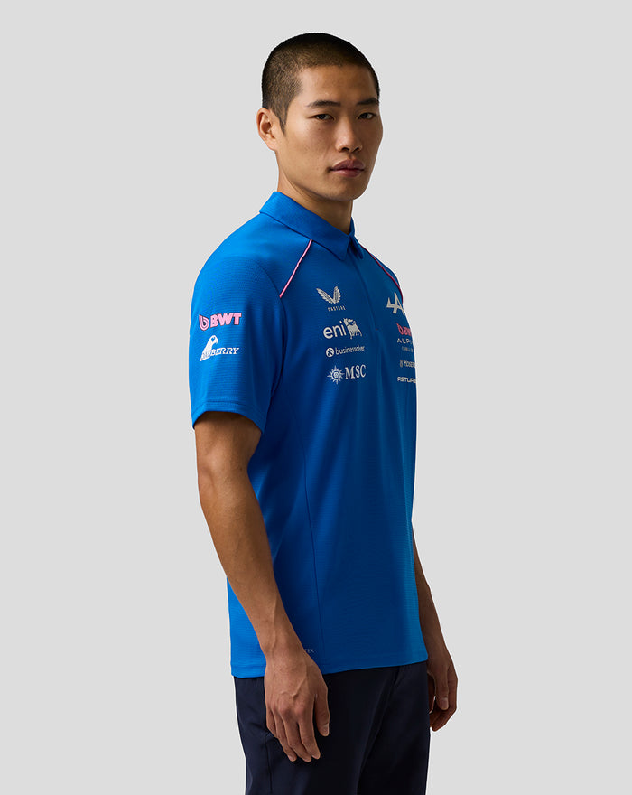 Side view of a man in a blue BWT Alpine Formula One Team polo with sponsor logos on the chest and sleeve