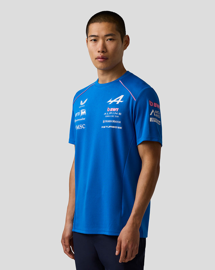 Side angle of male model wearing blue BWT Alpine Formula One Team T shirt with sponsor logos on chest and sleeve.