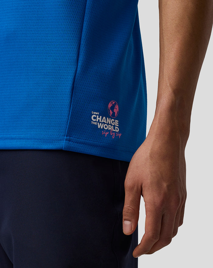 Side view of blue BWT Alpine polo with pink Change the World graphic near the hem.