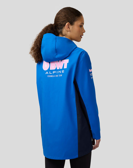 Back view of a woman in a lapis blue BWT Alpine water resistant jacket with a large logo on the back and navy side panels