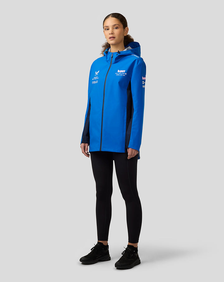 Female model wearing lapis blue BWT Alpine water resistant jacket with hood, center zip and sponsor logos.