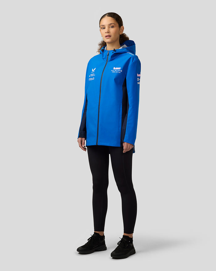 Female model wearing lapis blue BWT Alpine water resistant jacket with hood, center zip and sponsor logos.