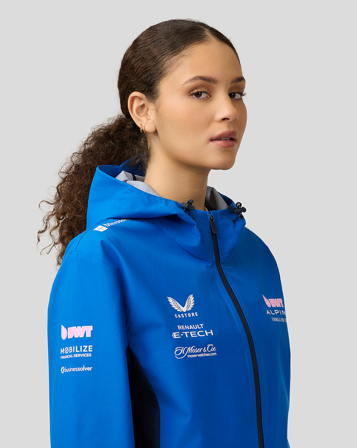 Female model wearing blue BWT Alpine water resistant jacket with hood from a side profile.