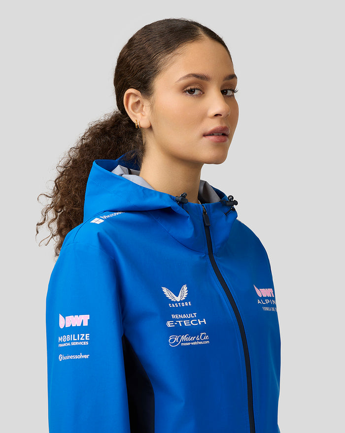 Female model wearing blue BWT Alpine water resistant jacket with hood from a side profile.