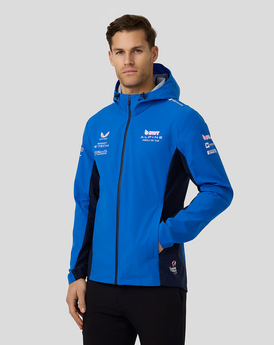 Model wearing BWT Alpine Formula One Team water resistant jacket in lapis blue with hood and sponsor logos.