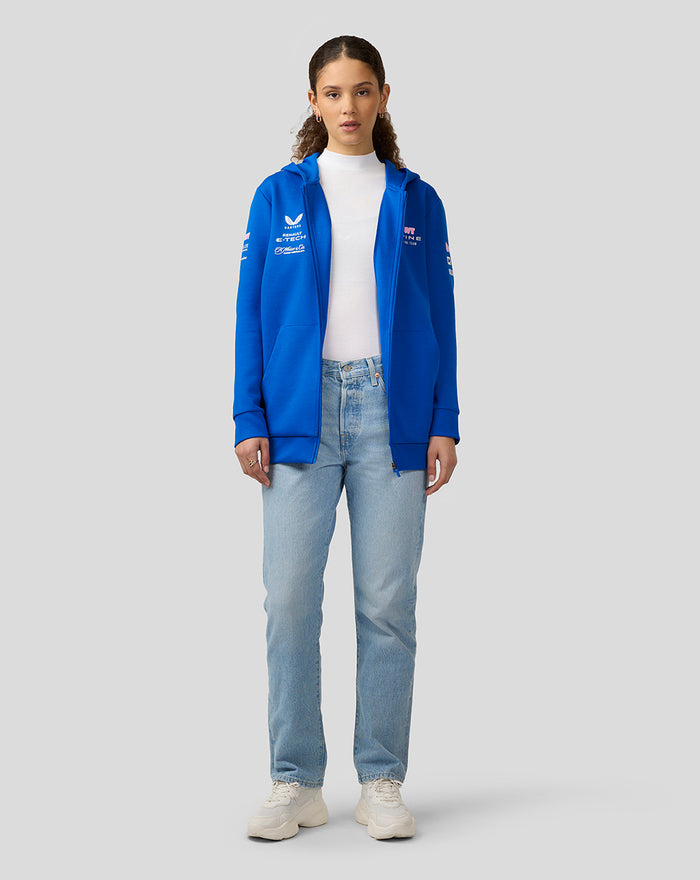 Female model in lapis blue BWT Alpine official full zip hoodie with logos on chest and sleeves over a white top.