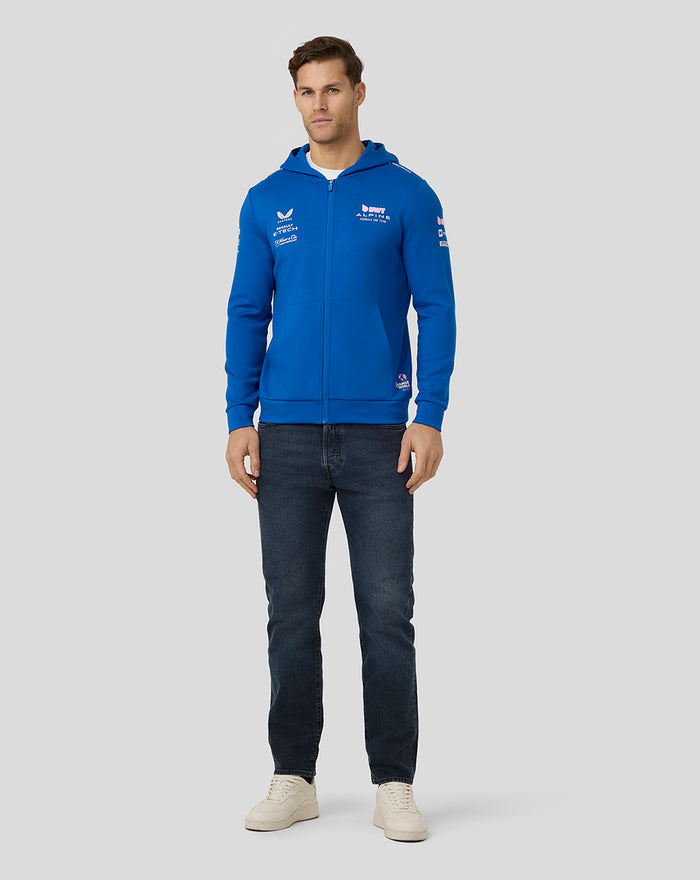 Male model in lapis blue BWT Alpine official full zip hoodie with chest logos and front pockets.