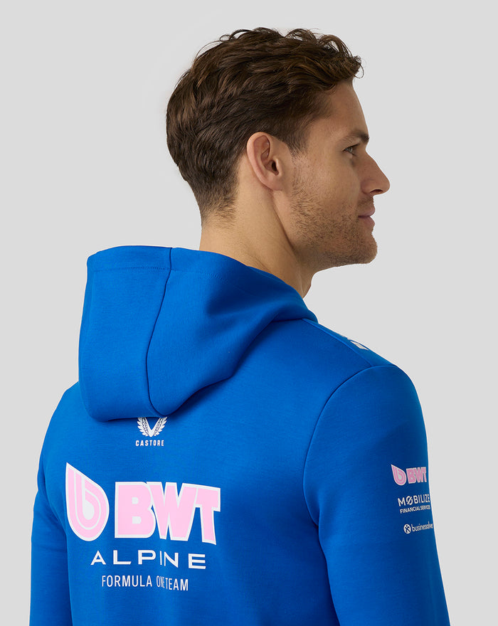 Back view of a male model in lapis blue BWT Alpine hoodie with a large pink BWT logo on the back