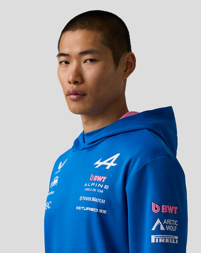 Portrait of a model in a blue BWT Alpine Formula One Team hoodie showing chest logos