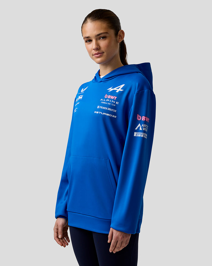 Female model in a bright blue BWT Alpine Formula One Team hoodie with chest and sleeve logos and Alpine branding on the back.