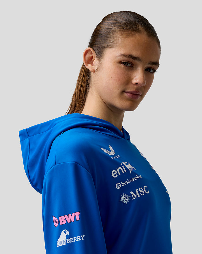 Side profile of a model wearing a blue BWT Alpine Formula One Team hoodie with chest and sleeve logos