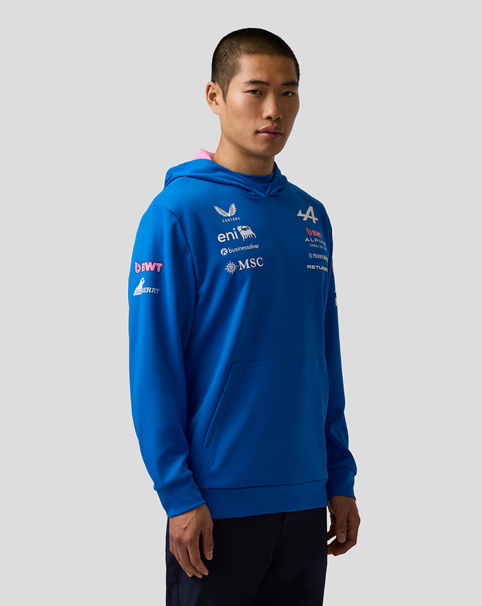 Male model in a bright blue BWT Alpine Formula One Team hoodie with chest and sleeve sponsor logos and pink lining at the hood.