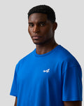 Male model wearing lapis blue relaxed fit T shirt with white embroidered A on left chest