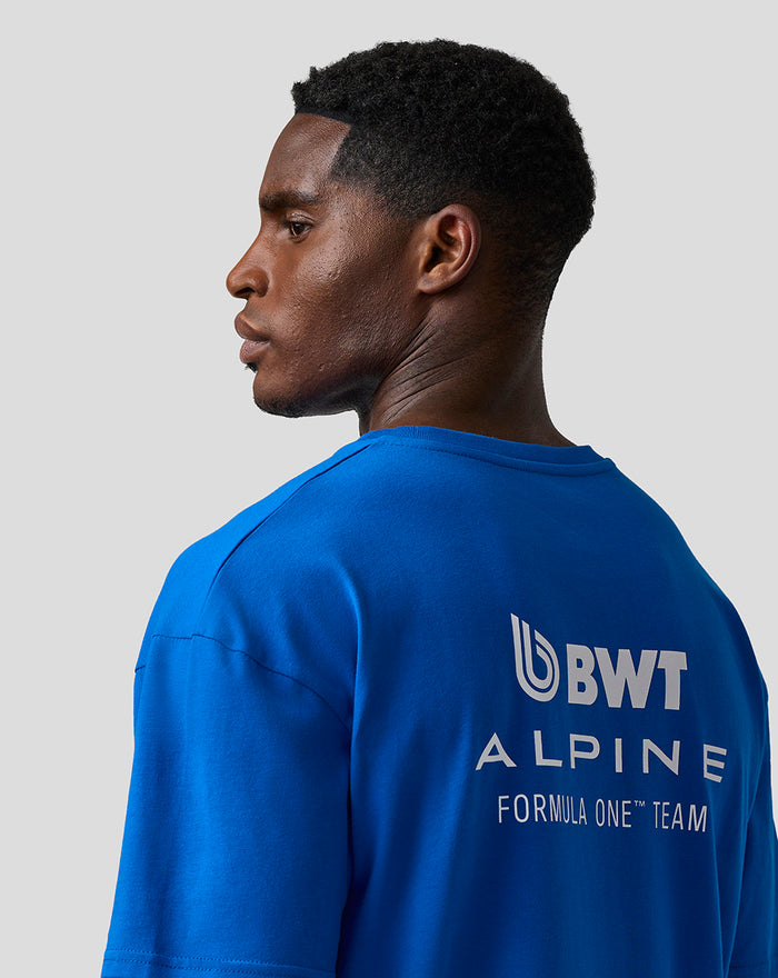 Side profile of a man wearing lapis blue BWT Alpine relaxed fit T shirt with a large logo on the back