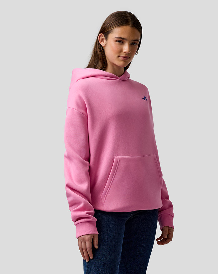 Female model wearing pink oversized hoodie with a small left chest logo and front kangaroo pocket.