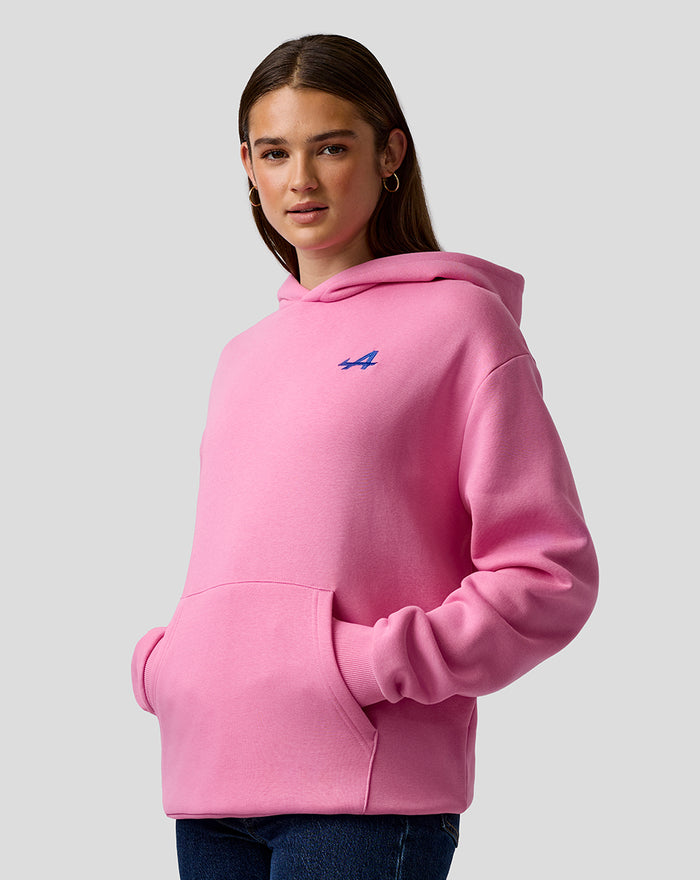 Woman wearing pink hooded sweatshirt with a blue embroidered A on the left chest and a kangaroo pocket.