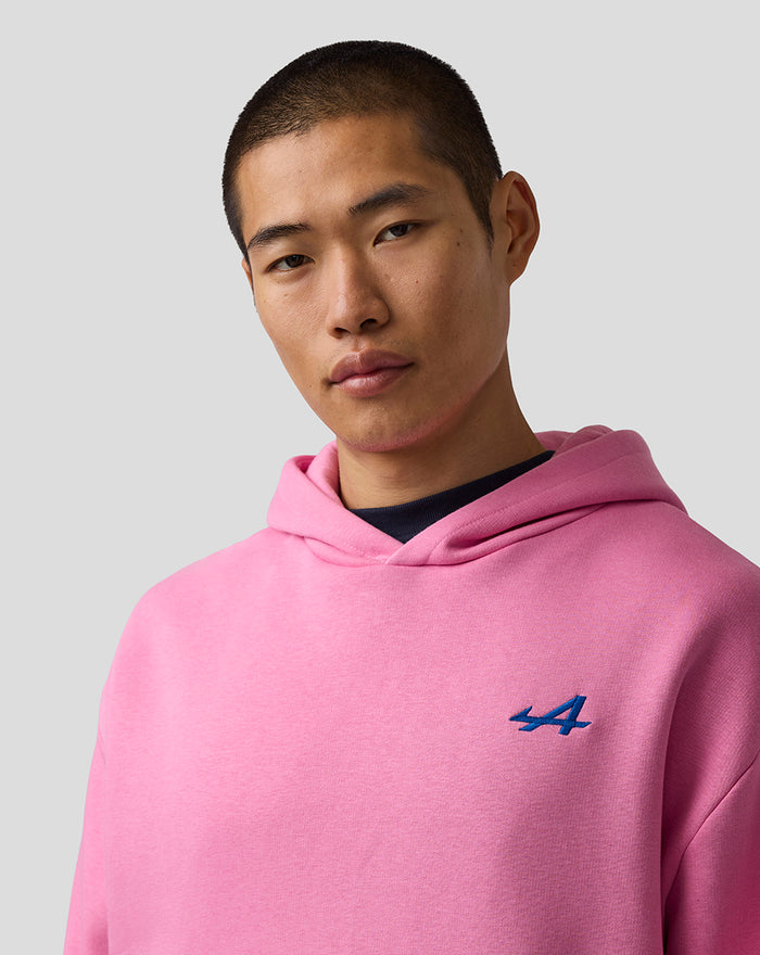 Close up of a man in a pink hooded sweatshirt with a blue embroidered A on the left chest.