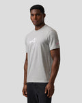 Man wearing grey marl unisex regular fit graphic T shirt with white Alpine chest graphic and pink Alpine A embroidery on sleeve