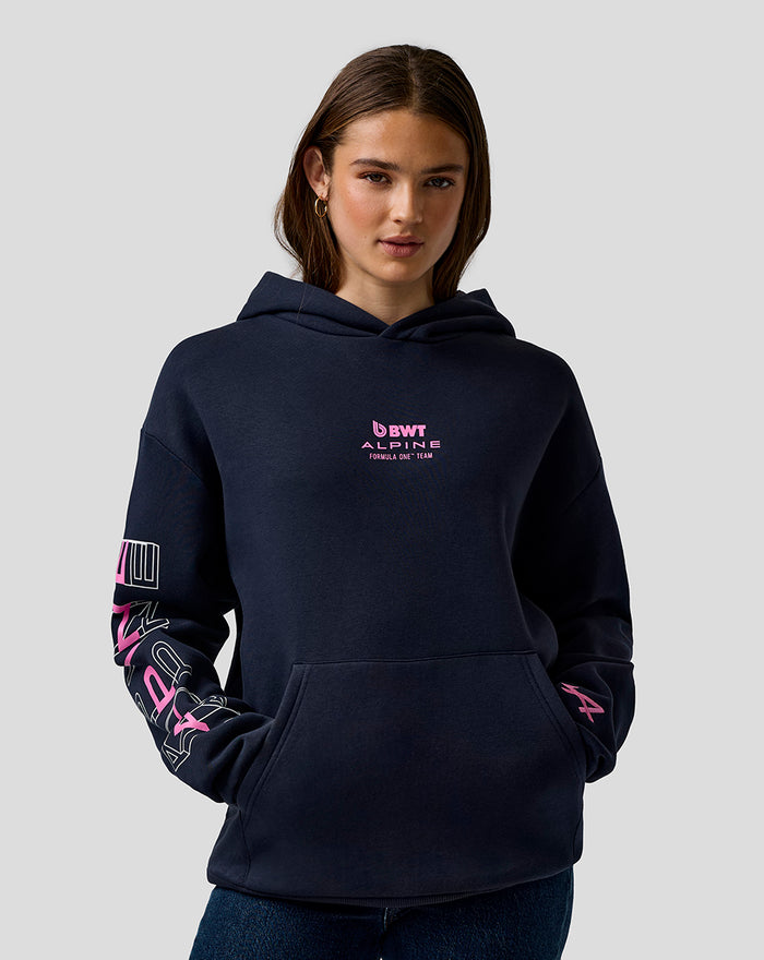 Female model in navy BWT Alpine graphic hoodie with chest logo and bold sleeve artwork