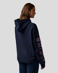 Woman in navy Relaxed Fit Graphic Hoodie Night Sky seen in profile with chest logo and pink Alpine graphic on the right sleeve