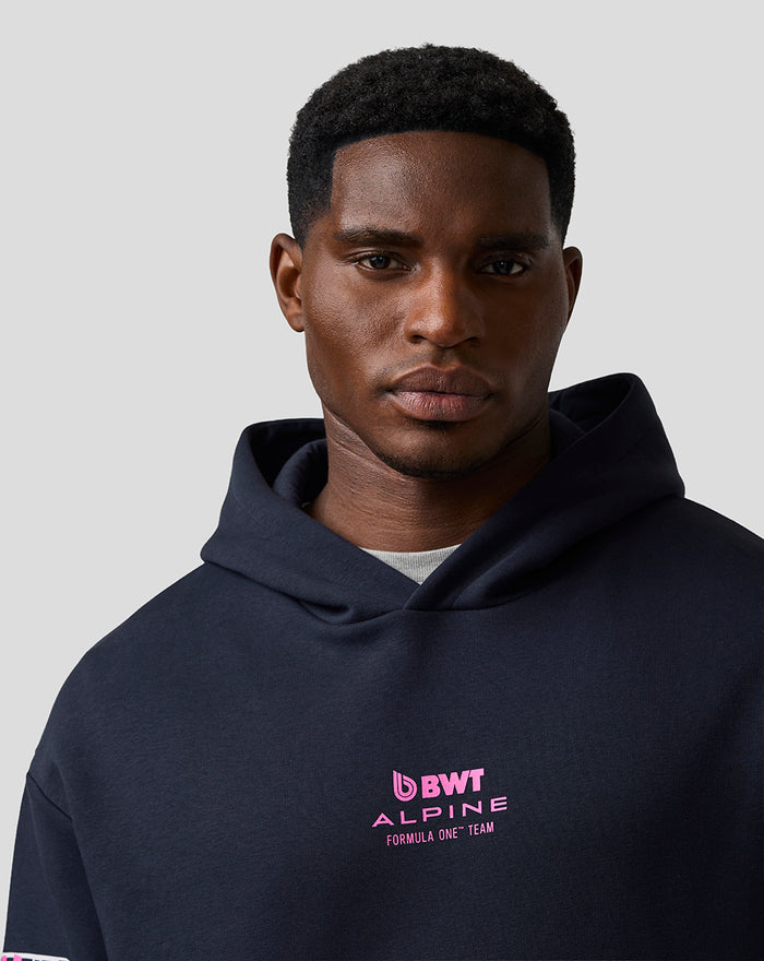 Close-up of man wearing navy BWT Alpine hoodie with pink chest logo and hooded design