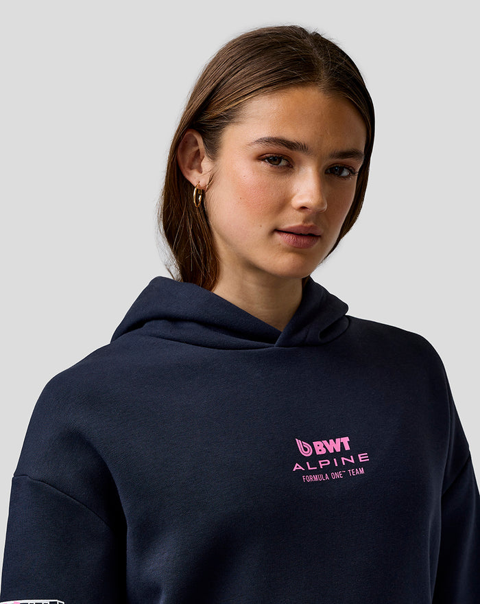 Close-up of woman wearing navy BWT Alpine hoodie with pink Alpine logo on chest